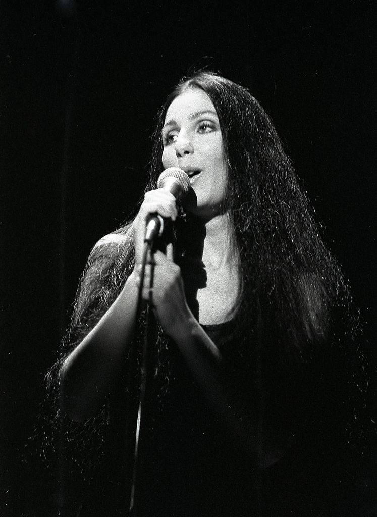 Sher sings into a microphone.