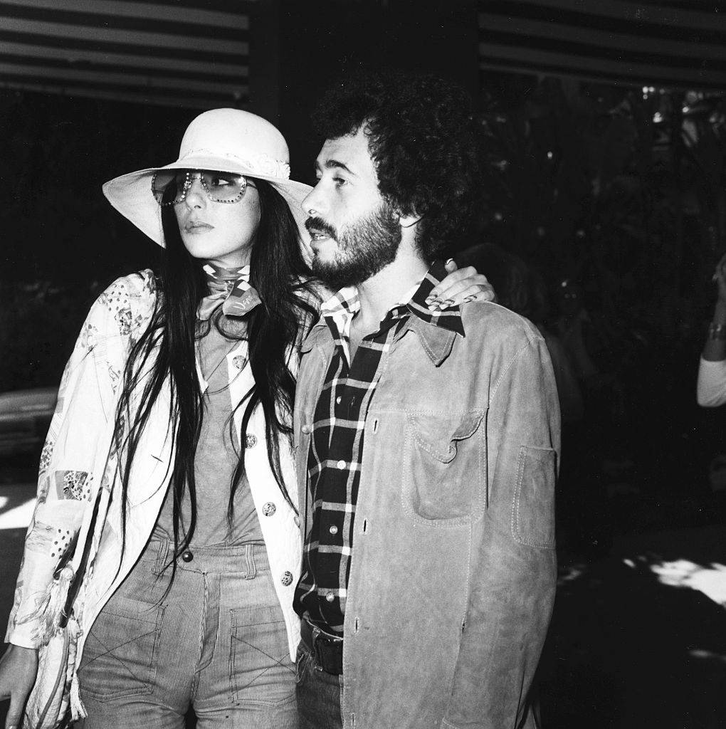 Cher puts her arm around David Geffen's shoulder.