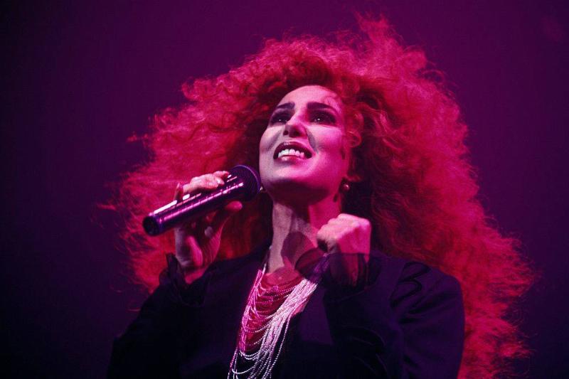 Cher has wild, curly red hair while performing onstage.