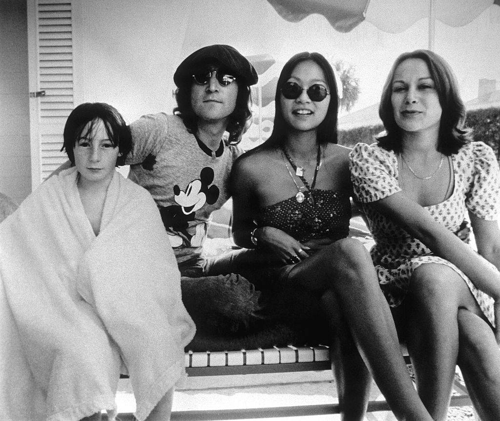 John Lennon puts one arm aroung May Pang and the other around Julian at a pool.