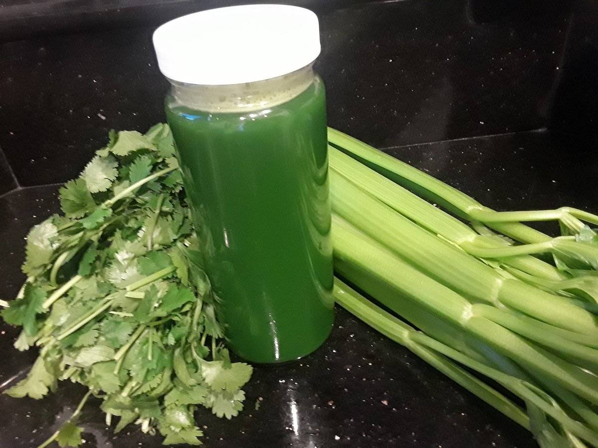 Juiced celery is in a bottle surrounded by whole celery.