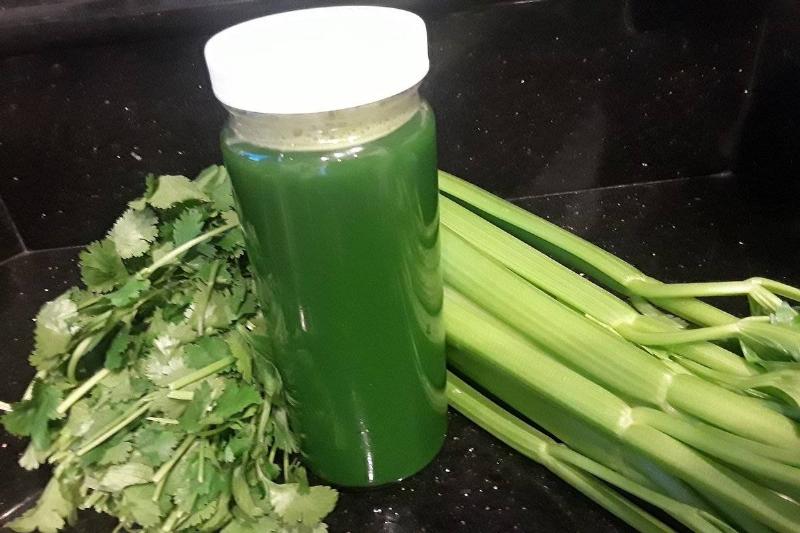 celery juice Juiced celery is in a bottle surrounded by whole celery.