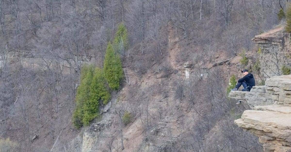 A man poses on the cliff at Dundas Peak.