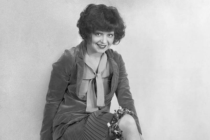 Clara Bow sitting on a bench 