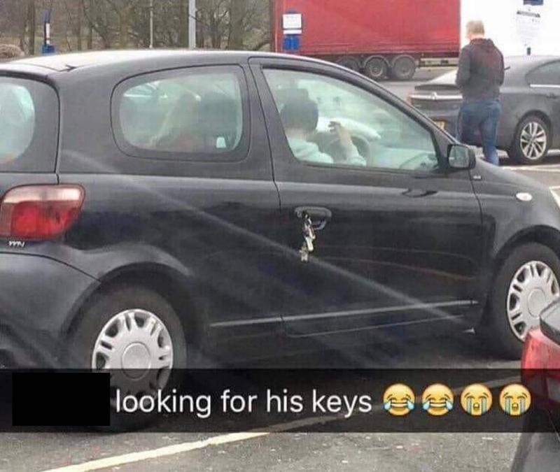 man looks for keys inside car while they're stuck on the outside in the door handle