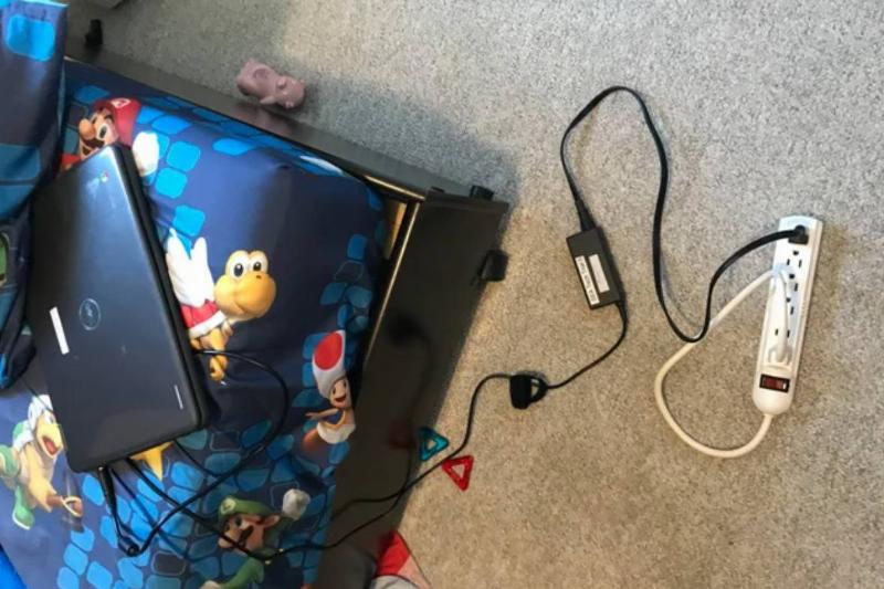 person with laptop plugged into a power bar that is also plugged into itself