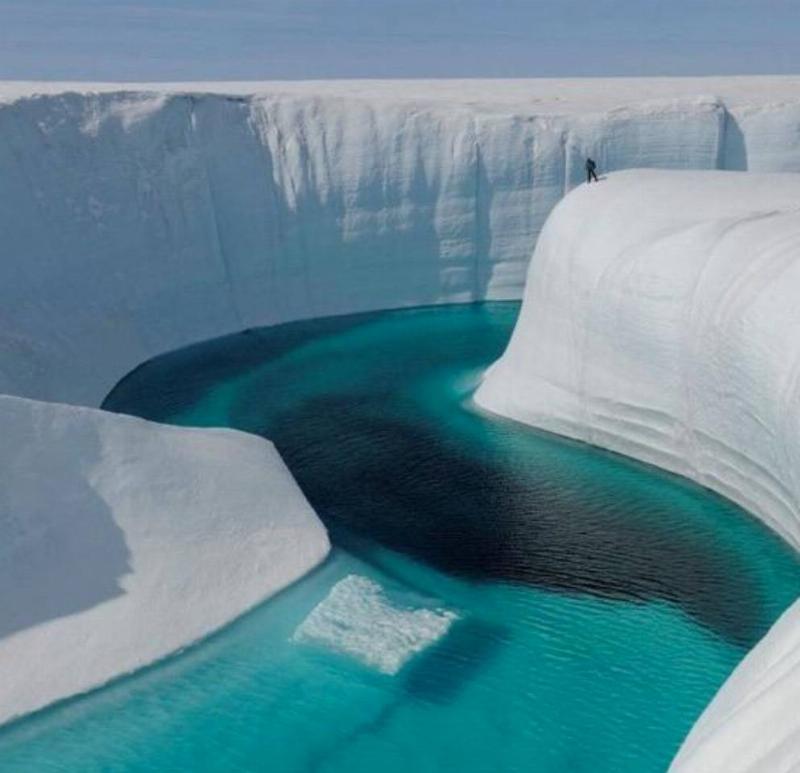 clear blue water stream through a gap in the ice