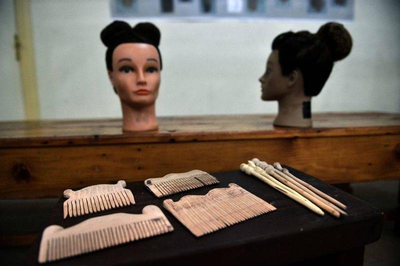 Ancient combs are displayed in from of ancient Greek hairstyles in a museum.