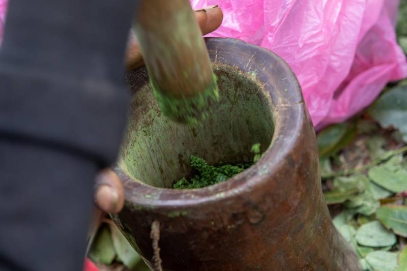 A Harari man grinds spices in a mortar and pestle.