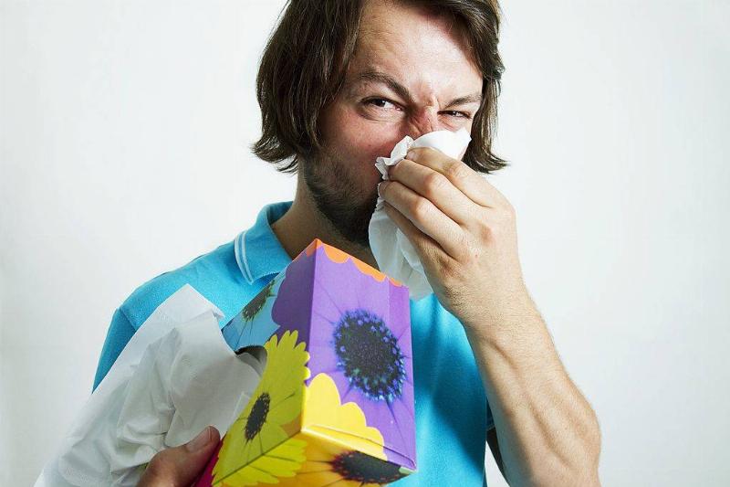 a man holding a tissue box and blowing his nose