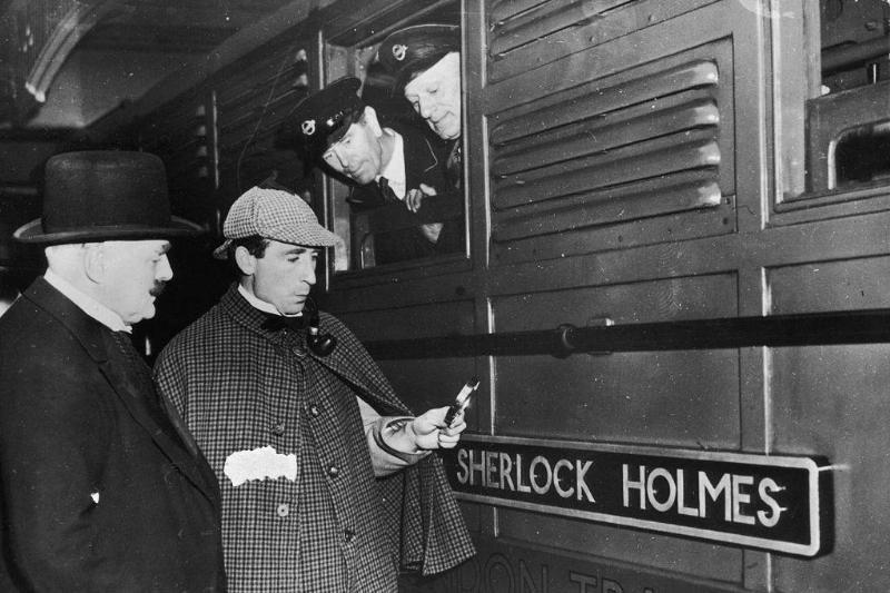 sherlock holmes holding a magnifying glass at a train 