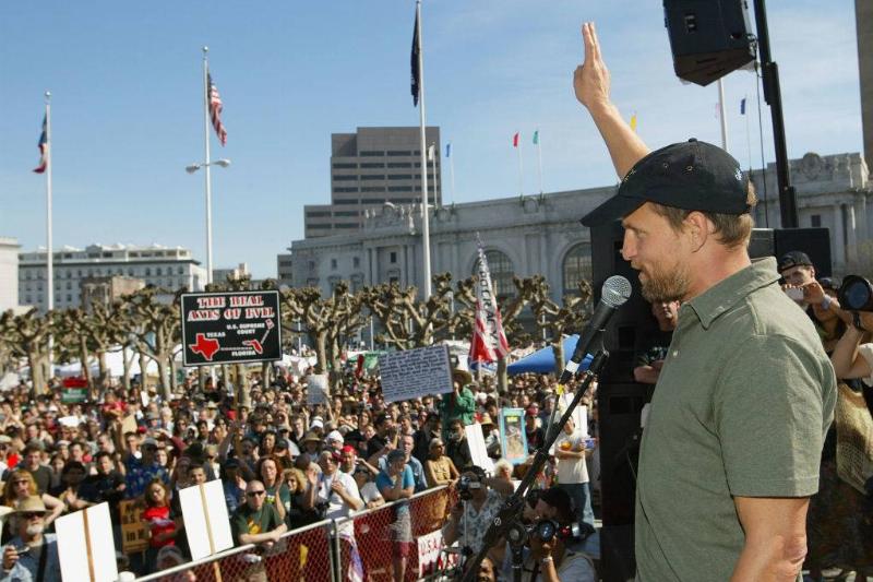 Actor Woody Harrelson flashes the peace sign to the crowd during an anti-war demonstration