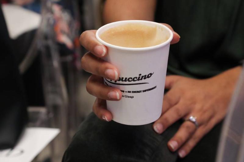 Cappuccino-1068464122 A woman holds a to-go cup of cappuccino.