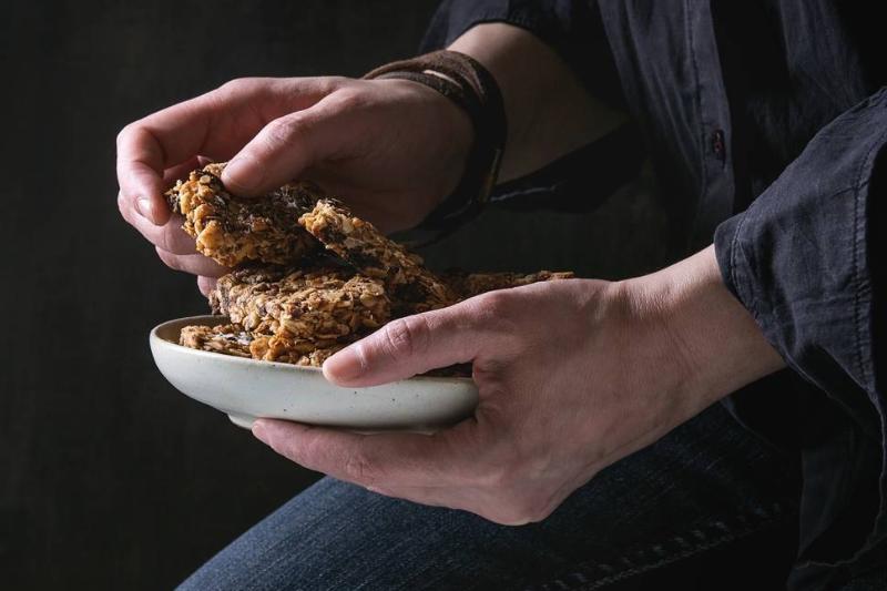 cereal bars - 1162328351 A woman picks up cereal bars from a plate.