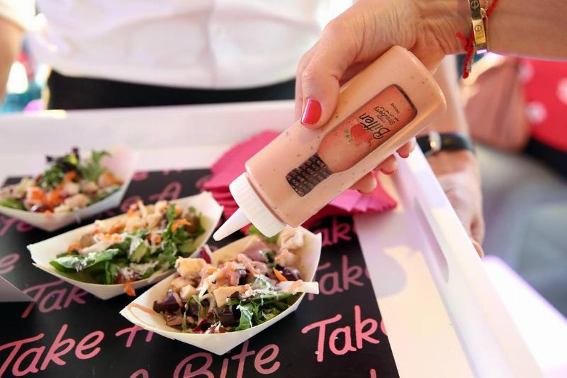 salad dressing - 1164056072 A woman pours salad dressing from a bottle onto a salad.