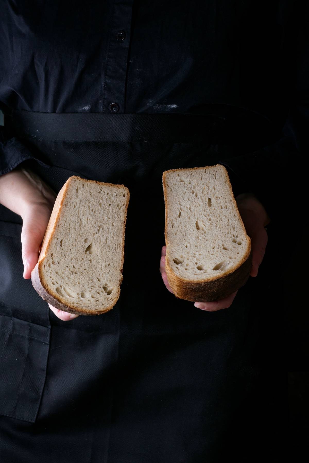 A woman holds two slices of white bread.