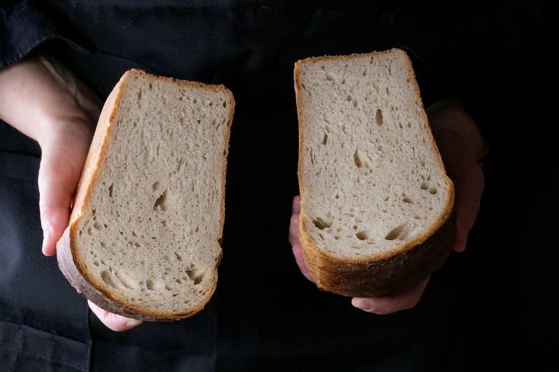 white bread-957728278 A woman holds two slices of white bread.