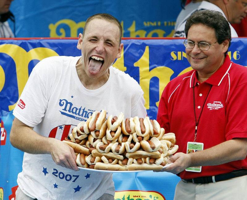 Joey Chestnut holding a plate of 66 hot dogs