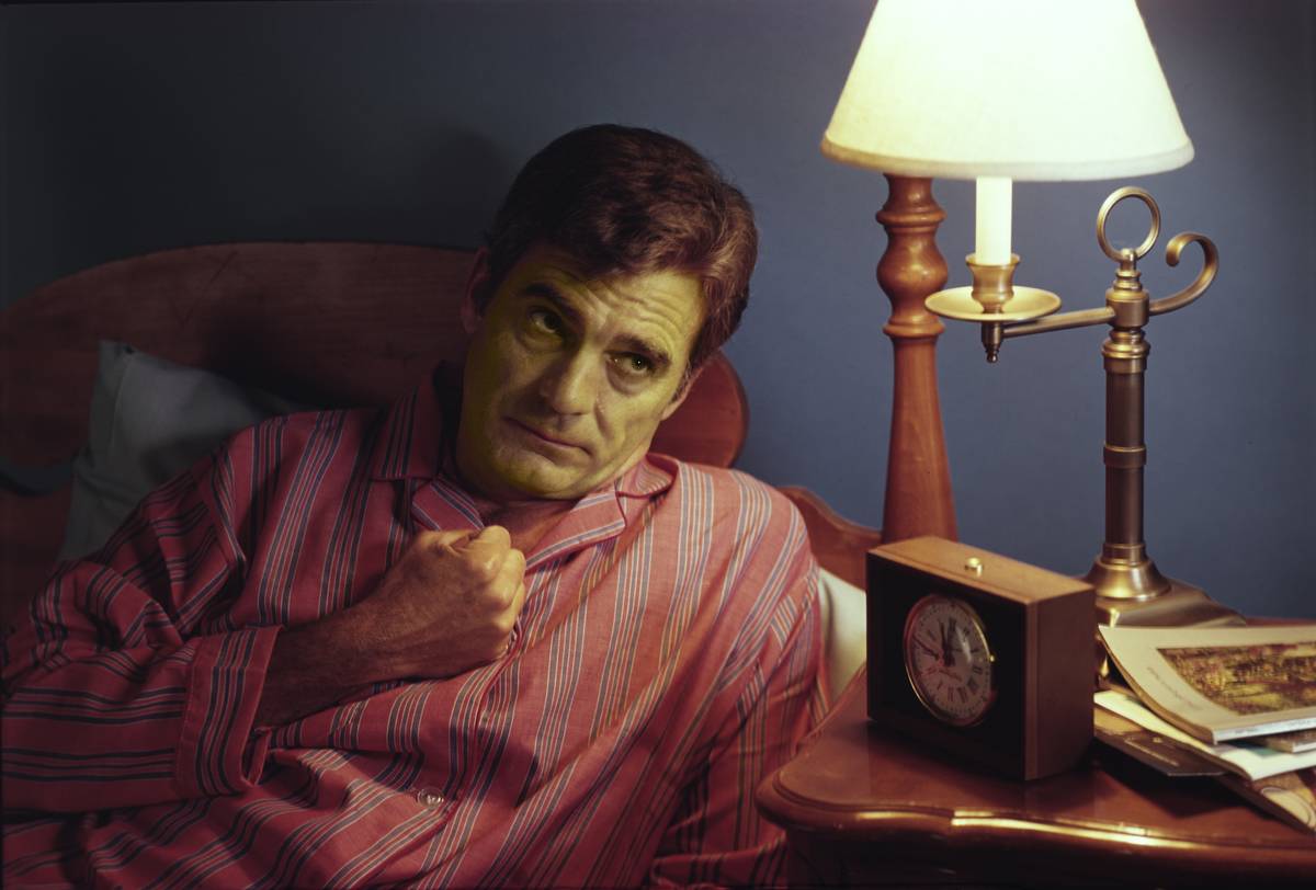 A man in bed suffers from heartburn.