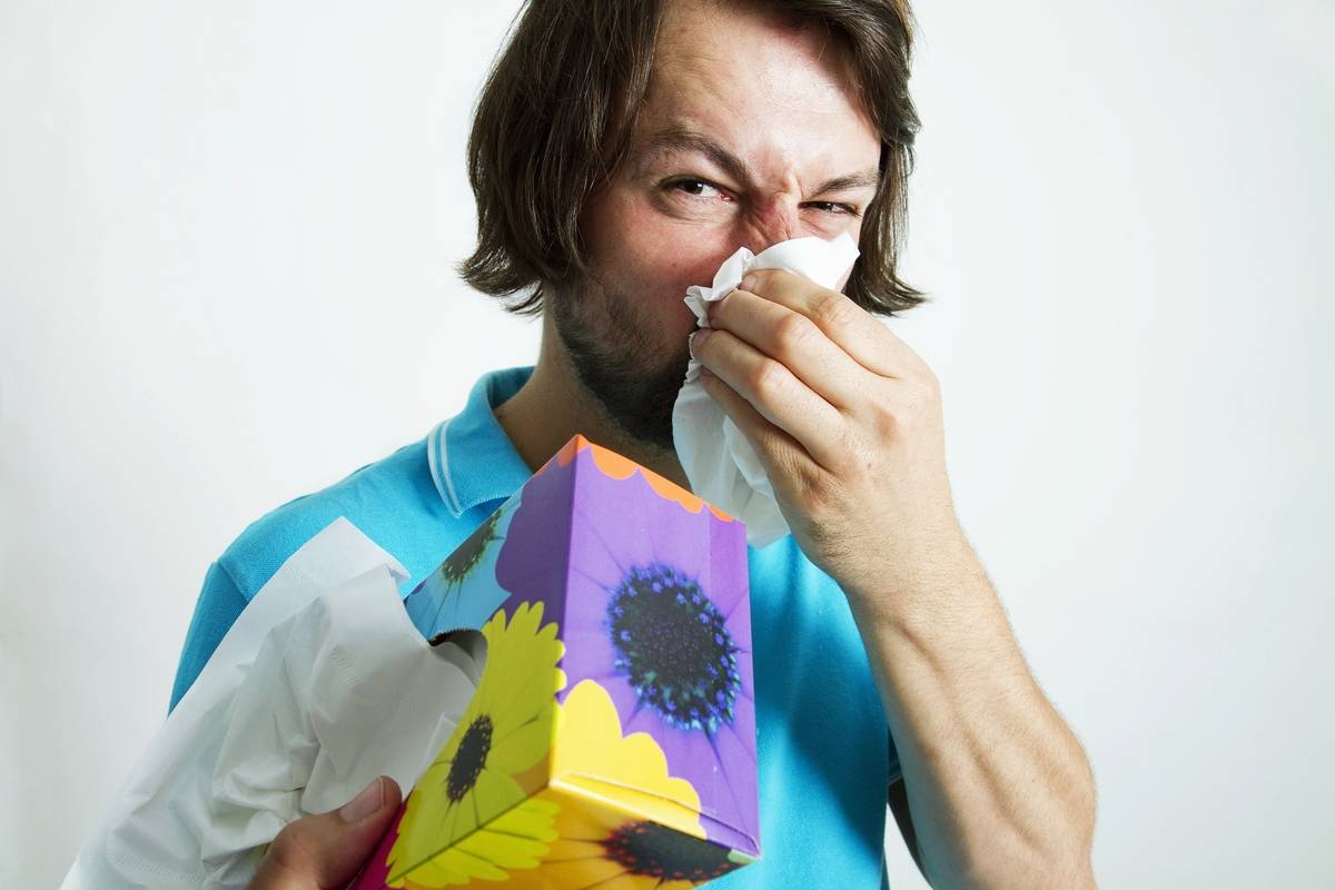 A man with a cold blows his nose.