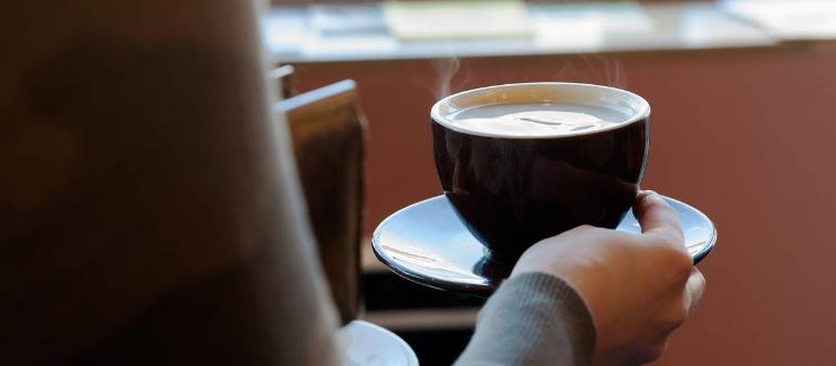A woman holds a cup of hot coffee.