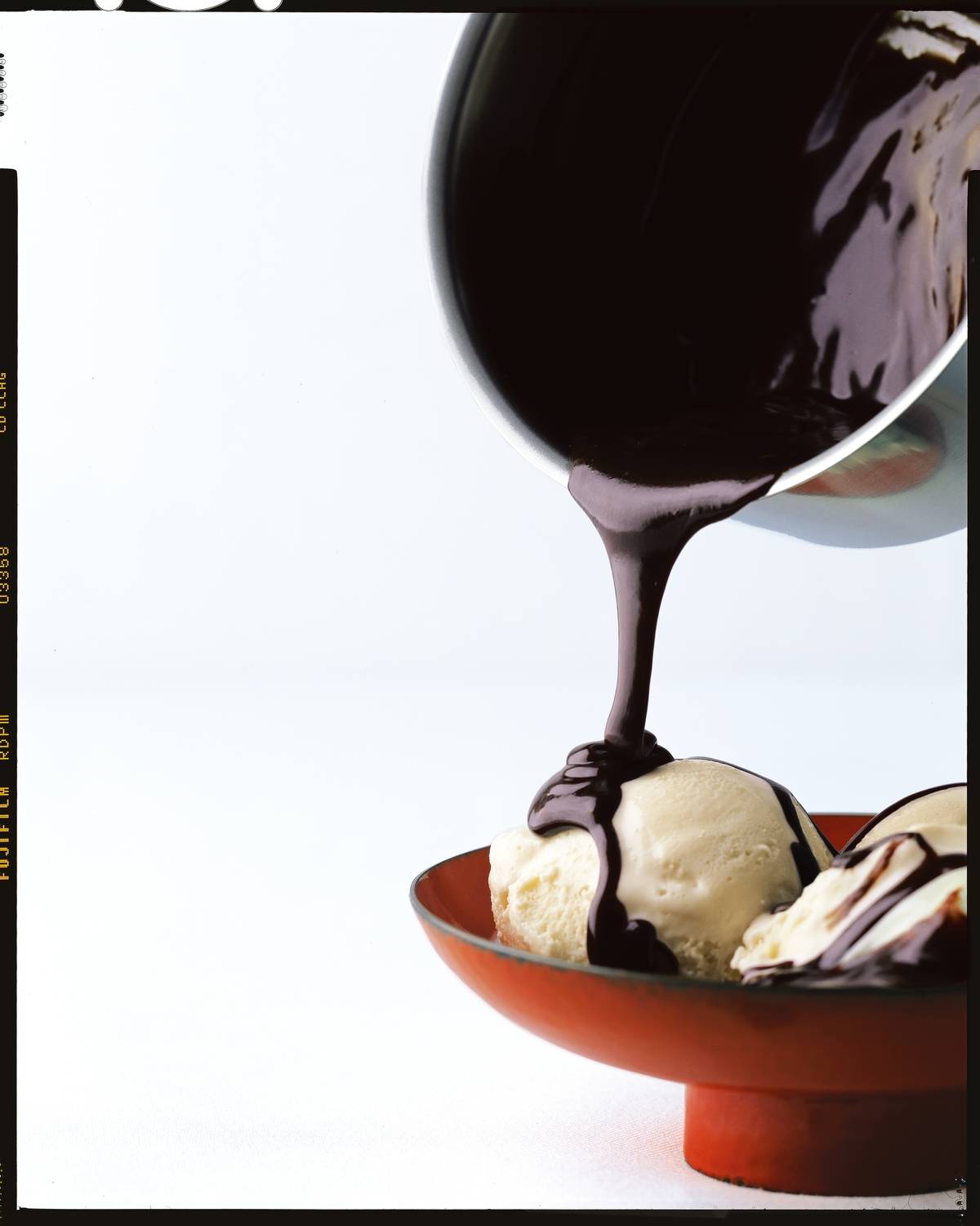 Chocolate sauce drizzles onto ice cream.