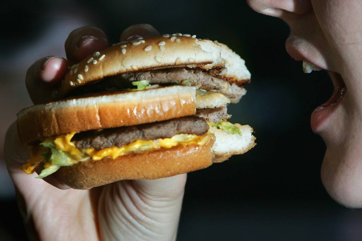 A woman eats a double cheeseburger.