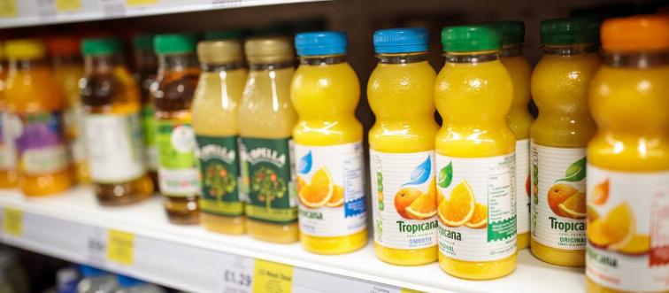 Plastic bottles of fruit juice sit on a grocery store shelf.
