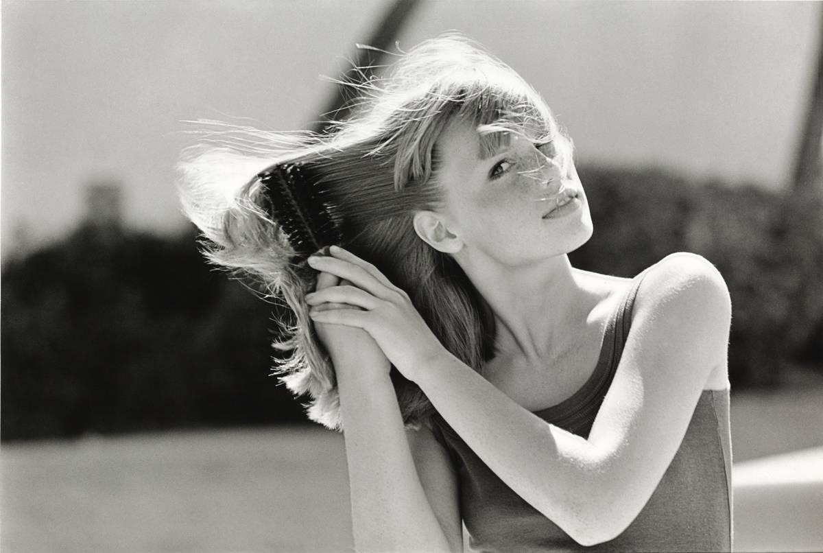 A woman brushes her hair.