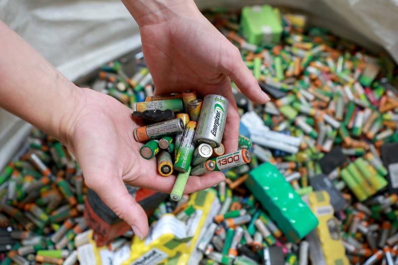 An employee holds recycled batteries in a recycling plant.