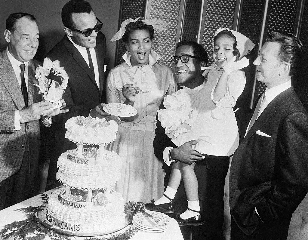 Lory White,23, enjoys a piece of the wedding cake, after her marriage to entertainer Sammy Davis Jr. Here Jan.10th. Davis is holding his sister, Suzzette Gina,4.