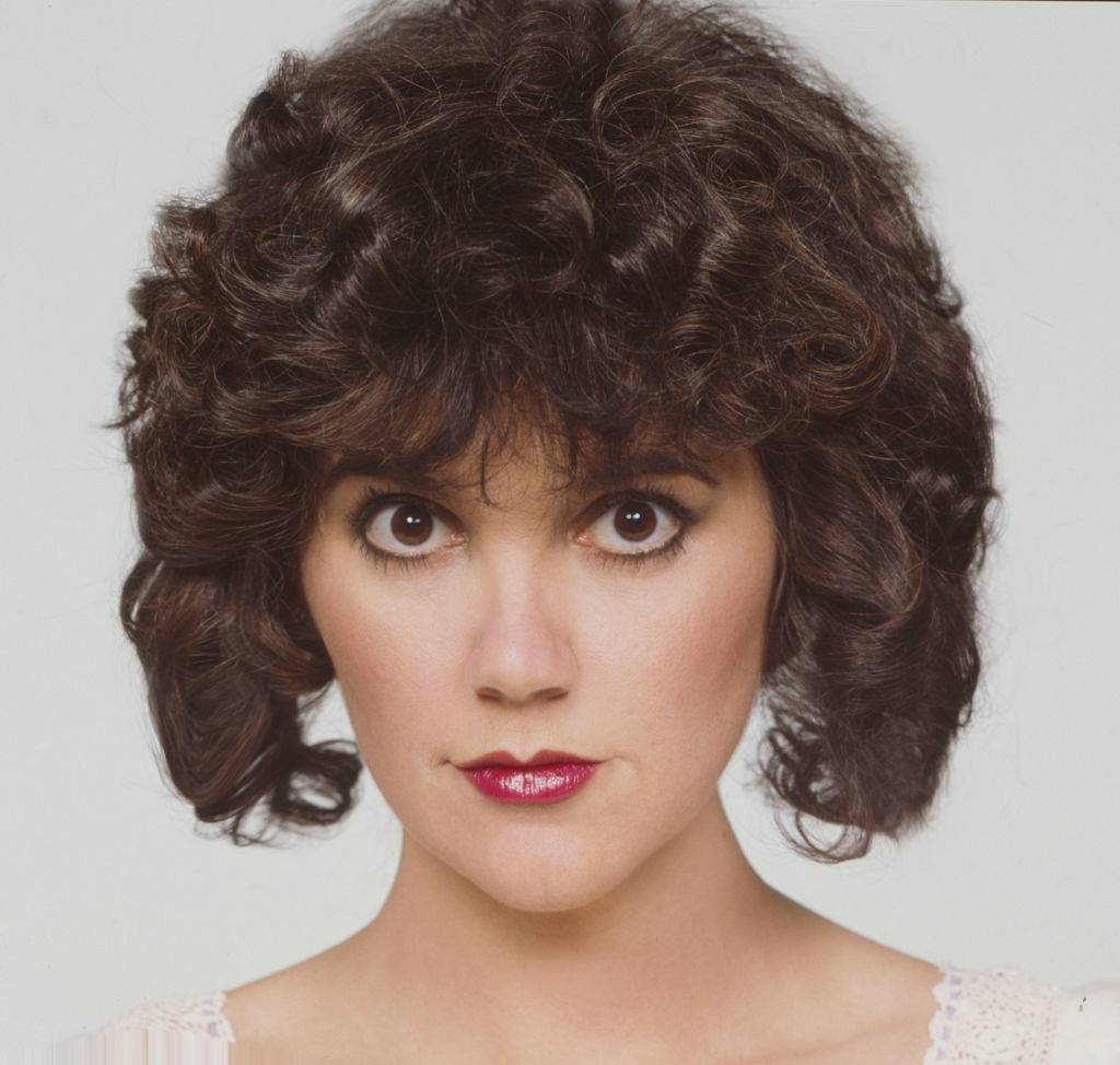 A portrait of Linda Ronstadt wearing pink lipstick