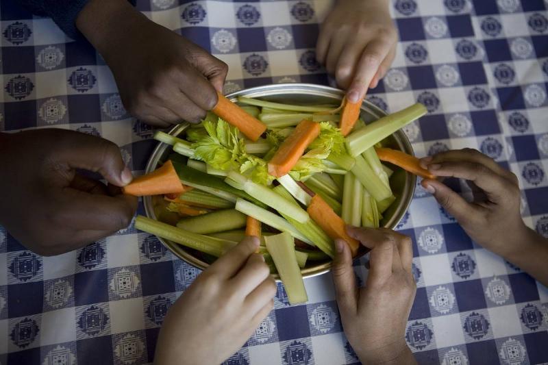 Students pull carrot and celery slices from a plate.