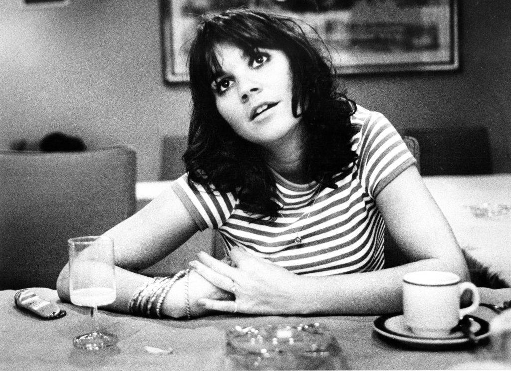 Linda Ronstadt wearing a striped shirt and drinking