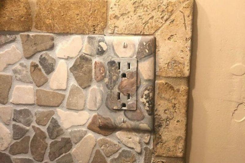 outlet painted to look like rocky backsplash in kitchen