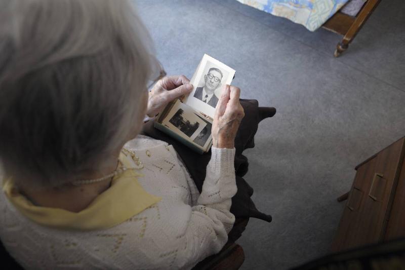 A woman with Alzheimer's looks through old photos.