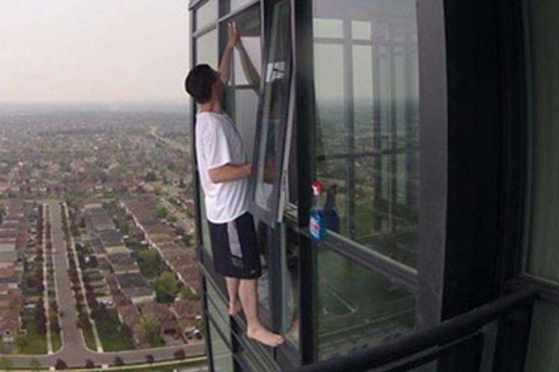 on the side Person cleaning window on high rise building without any safety harness