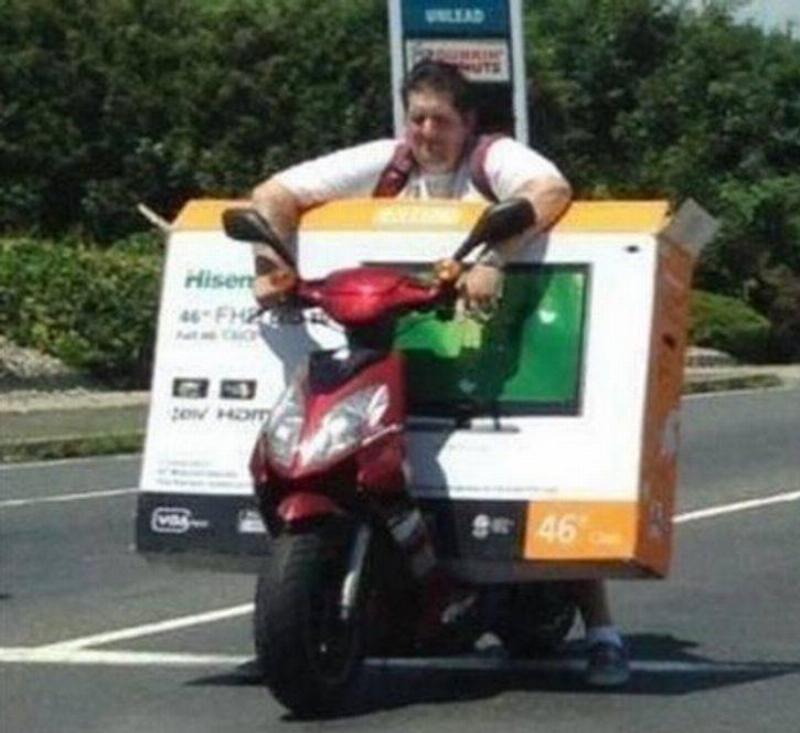 tv on small bike Person trying to transport oversized TV on a moped