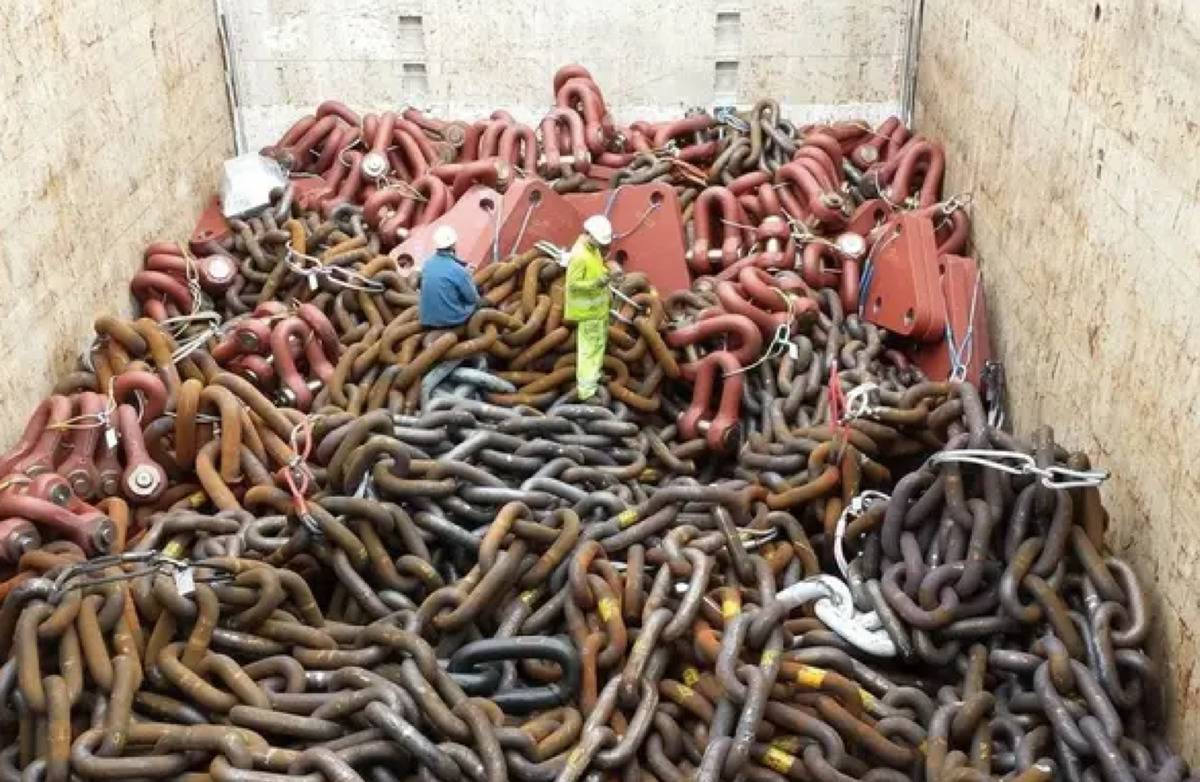 2 men standing on a bunch of really huge chains 