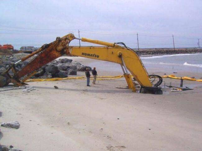 crane that's sinking into sand on beach