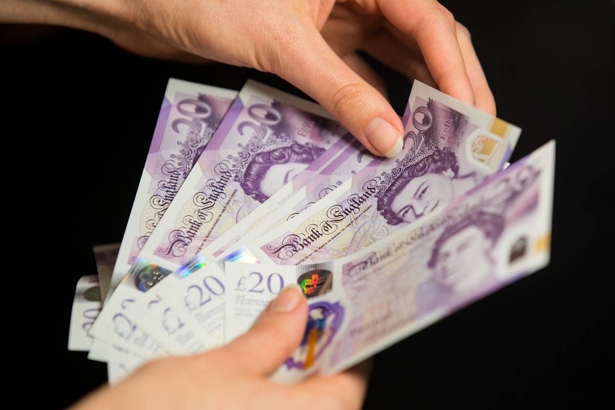 A woman holds bills of British banknotes.