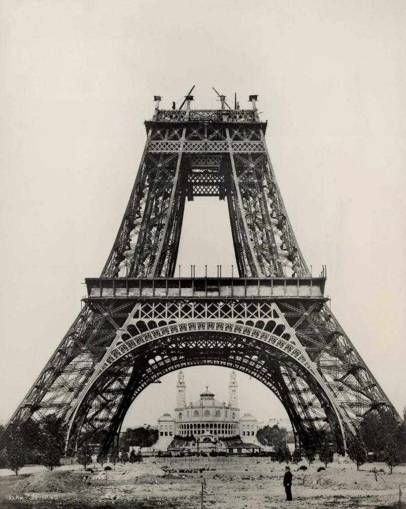 Gustave Eiffel stands at the base of the Eiffel Tower while it is under construction.