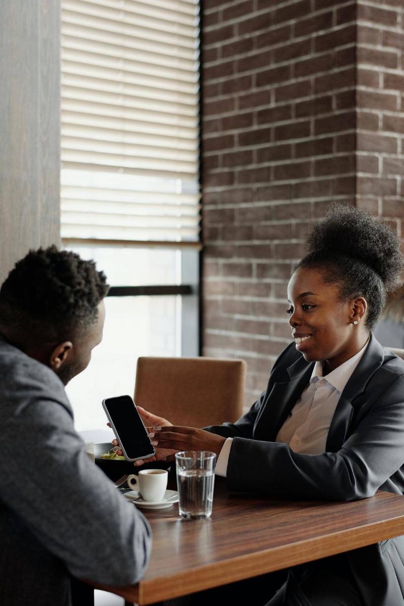 two people sitting in a coffee shop looking at her phone 