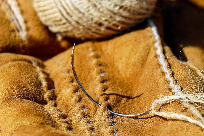 A needle is stuck through leather.