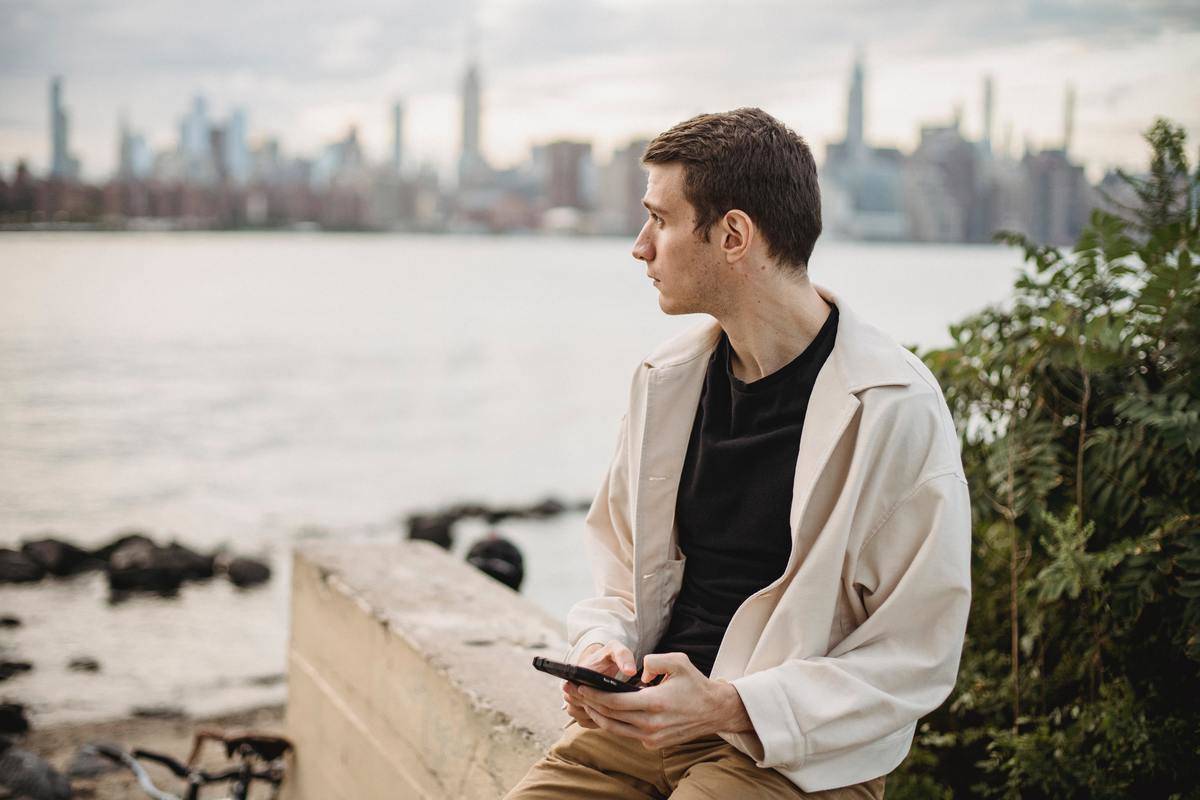 a guy leaning against a wall looking at the horizon 