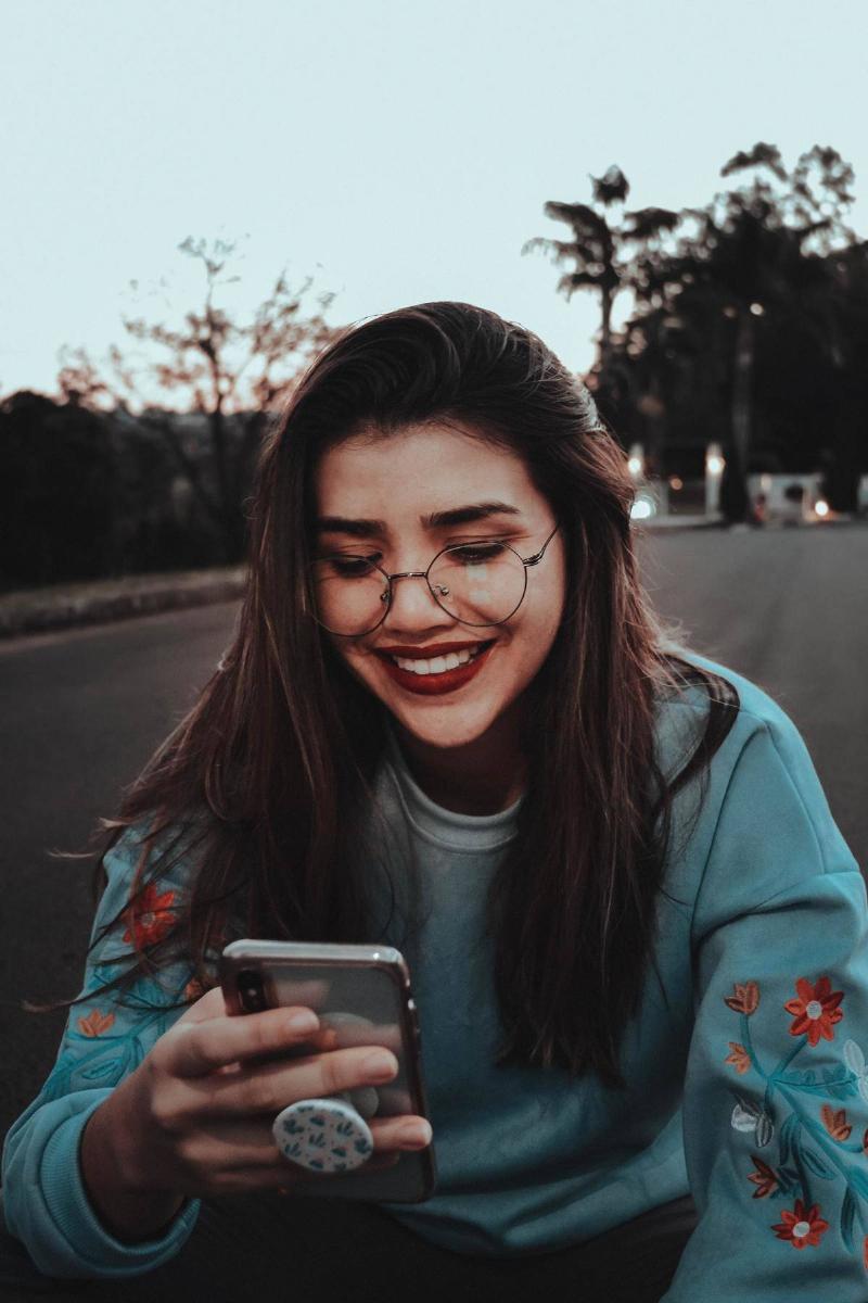 a woman smiling at her phone 