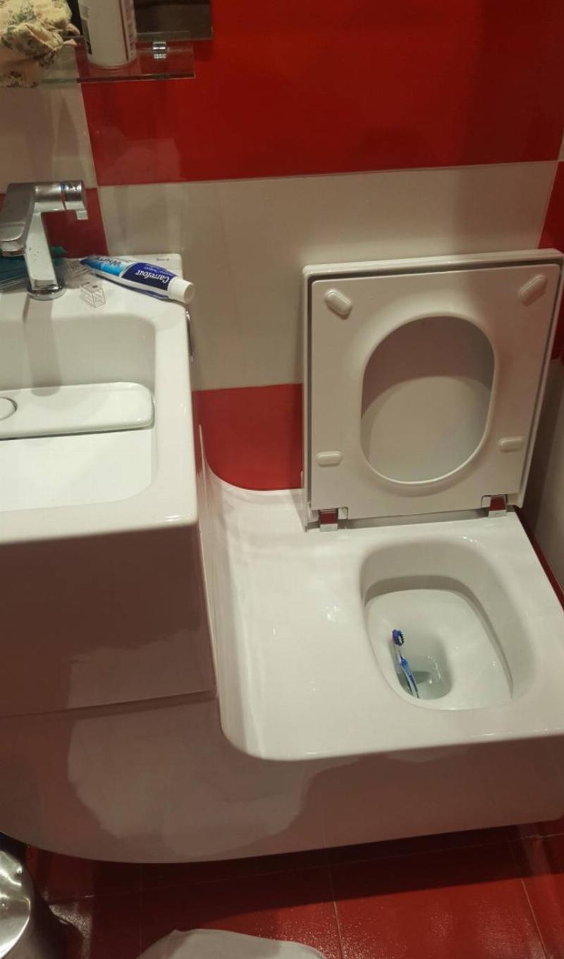 toilet sink counter has slope attaching it to toilet with toothbrush inside the toilet
