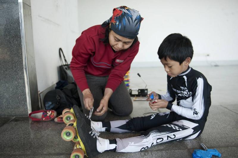 mom helping son put on roller skates