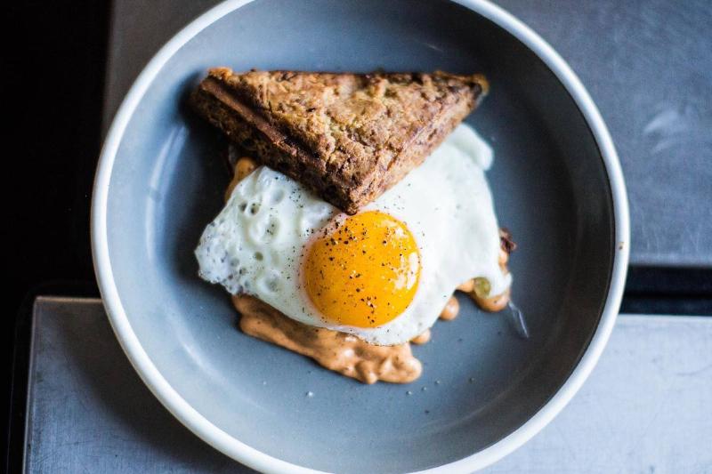A sunny-side-up egg is on top of toast and peanut butter.
