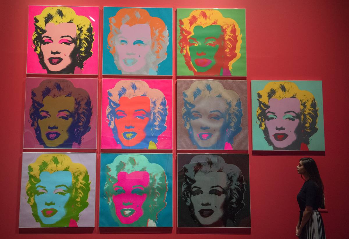 Woman walking past various pop art prints of Marilyn Monroe, made by Andy Warhol